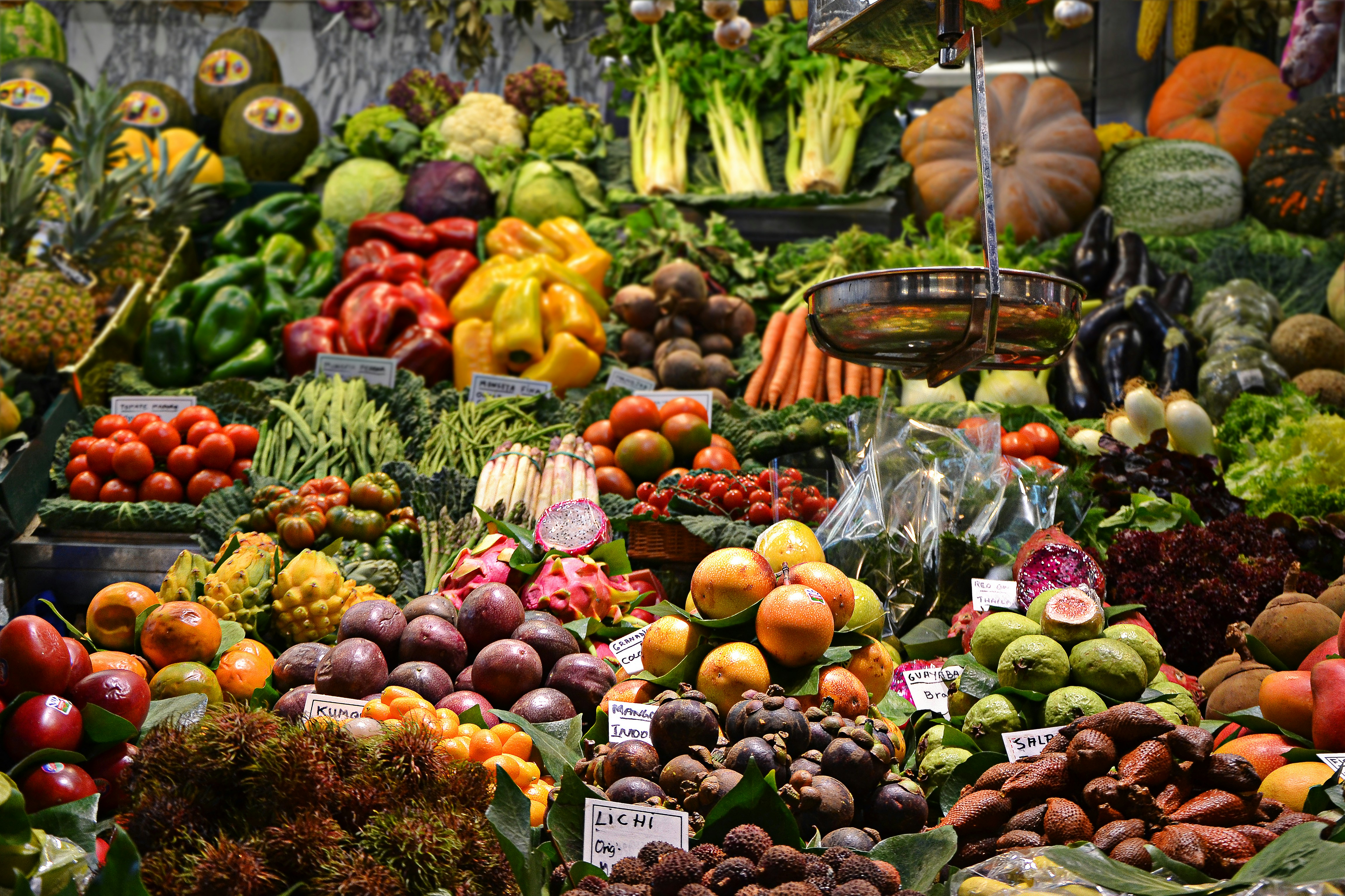 A colorful picture of various fruits and vegetables in a stall at Mercado de la Boqueria in Barcelona.