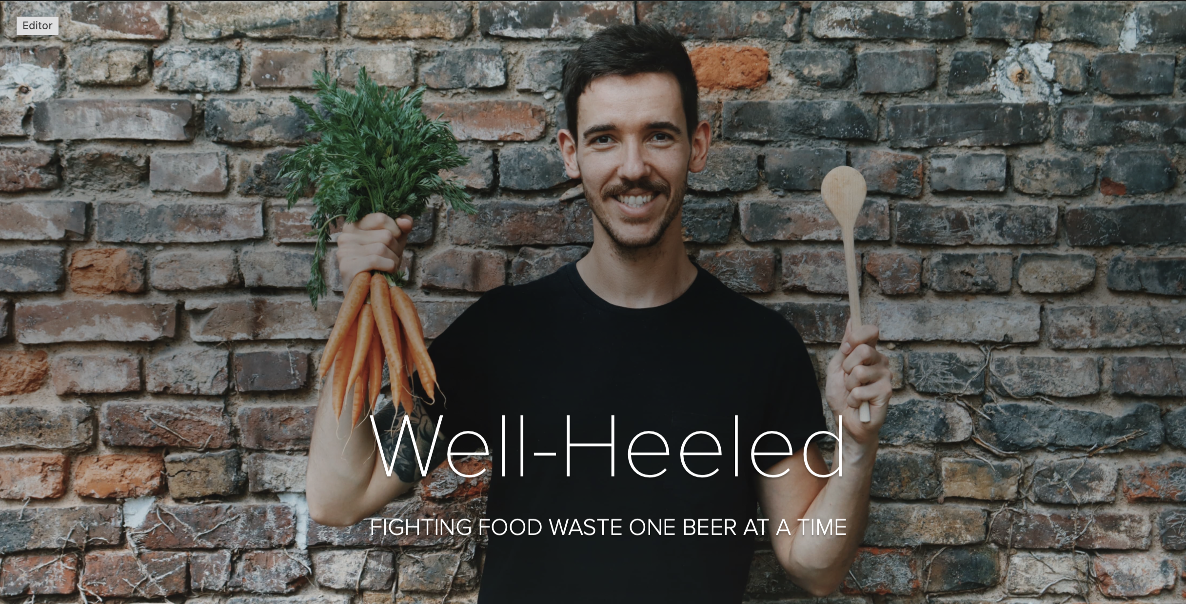 Daniel Anthes holding a bunch of carrots and a wooden spoon in front of a stone wall. The title reads "Well-Heeled: Fighting food waste one beer at a time""