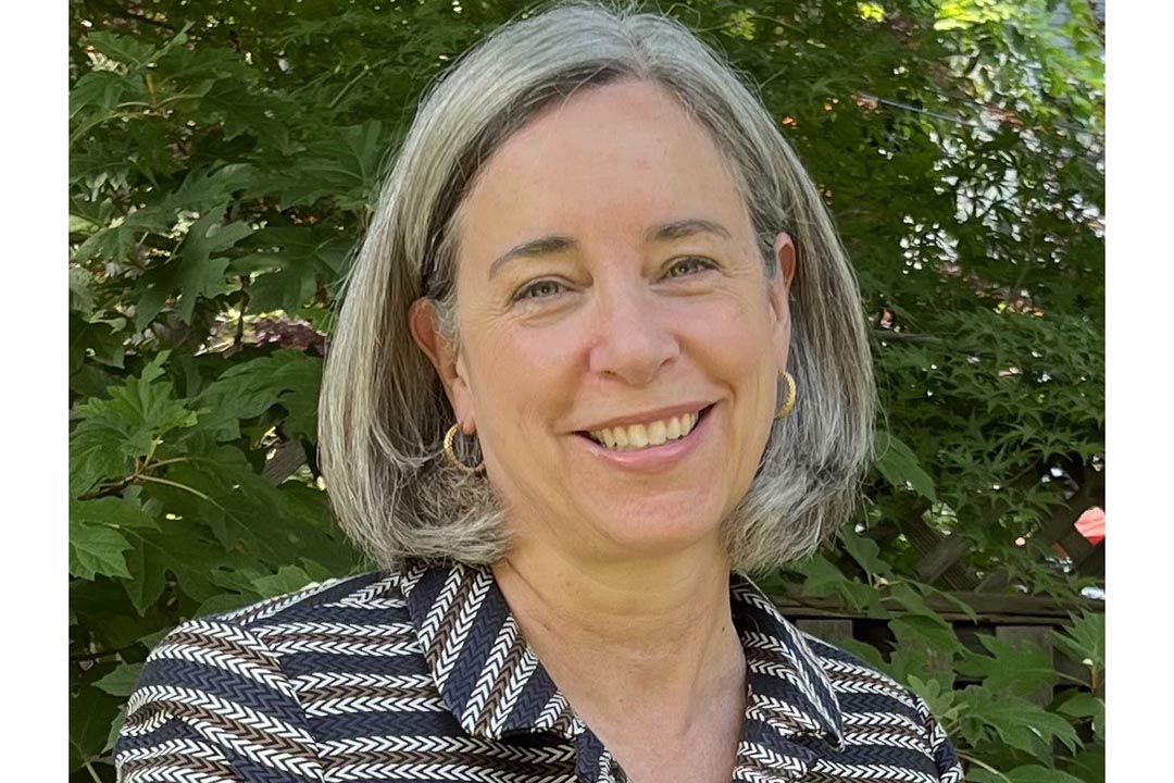 Headshot of Stacy Dean, behind her is a green bush like background
