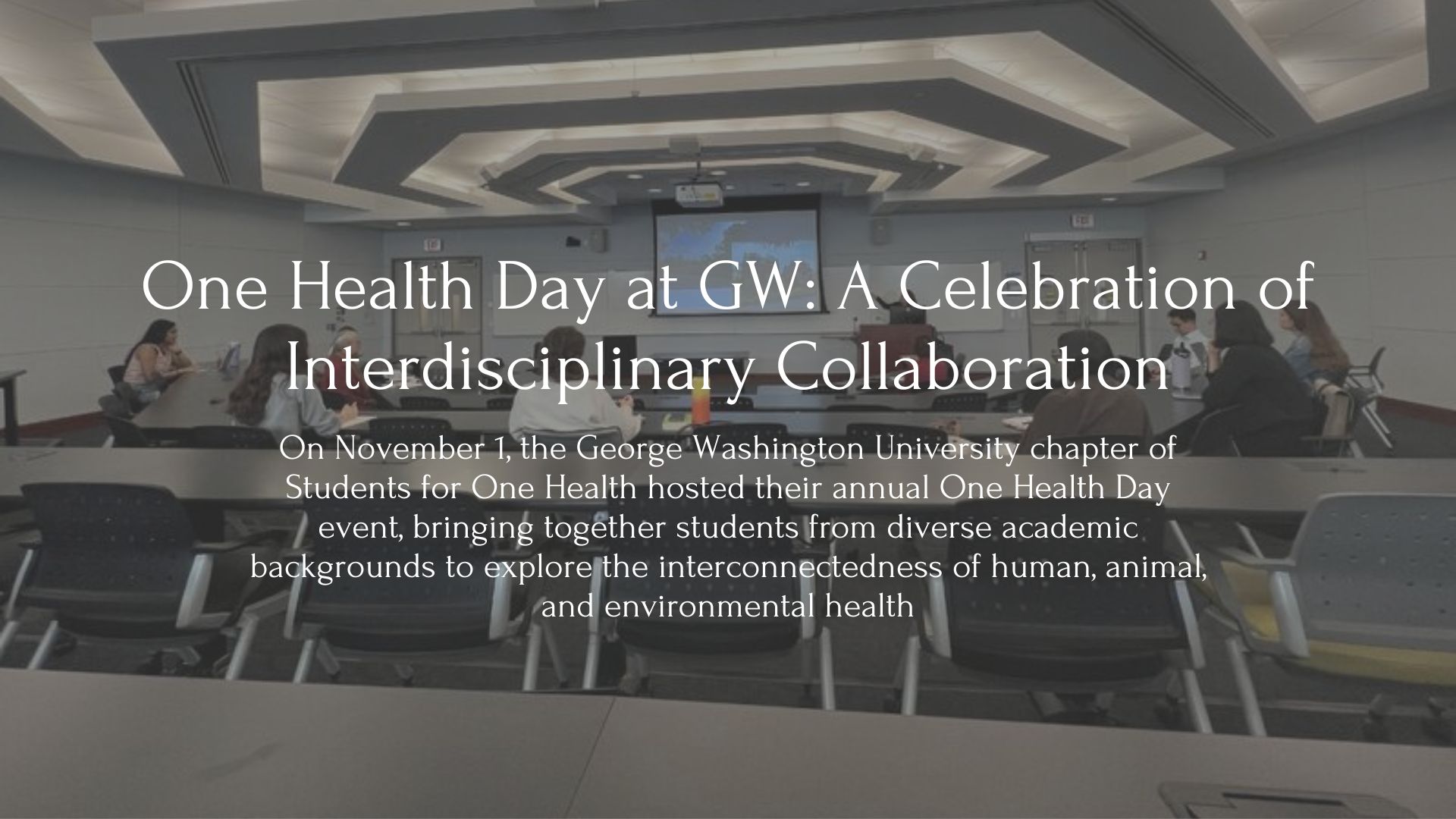 Picture with words in front, Title: One Health Day at GW: A Celebration of Interdisciplinary Collaboration. Subtitle: On November 1, the George Washington University chapter of Students for One Health hosted their annual One Health Day event, bringing together students from diverse academic backgrounds to explore the interconnectedness of human, animal, and environmental health. Picture features students in a classroom