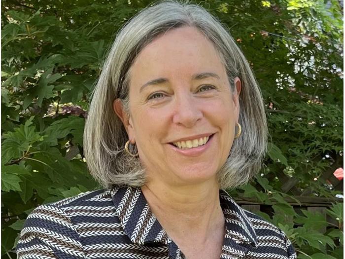 Headshot of Stacy Dean, behind her is a green bush like background