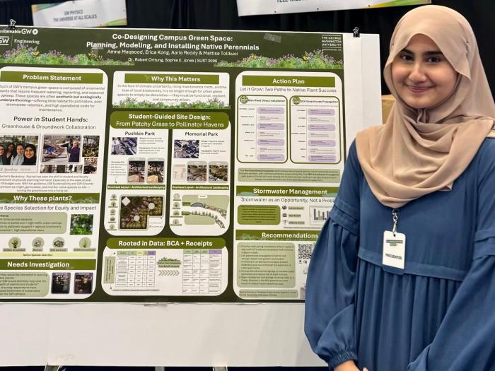 a student in a blue shirt stands in front of a green science poster