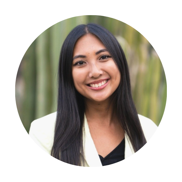 Edralin a woman with long dark hair in a cream blazer in front of a green outdoor background