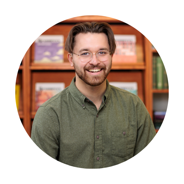 nick roy a man with glasses and green shirt in front of a library book case