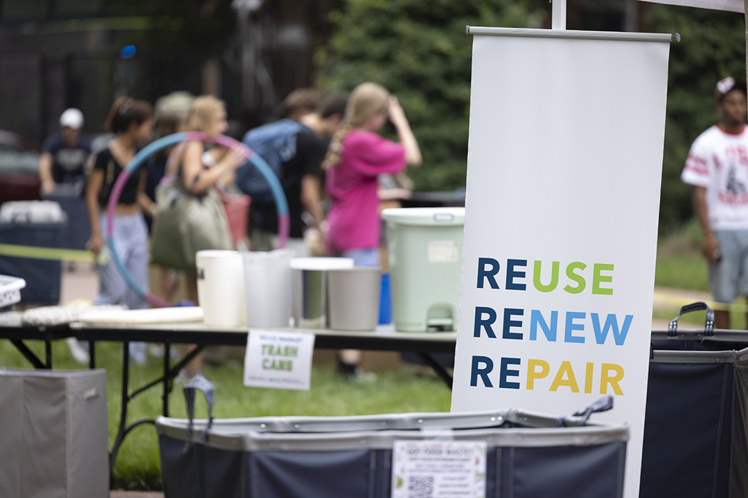 a white banner with the words REUSE RENEW REPAIR sits in the middle of a yard sale