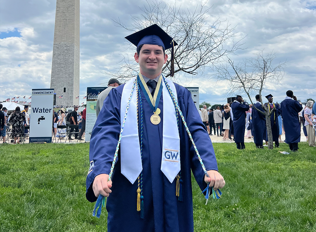 a recent GW graduate shows off his sustainability minor cords near the washington monument