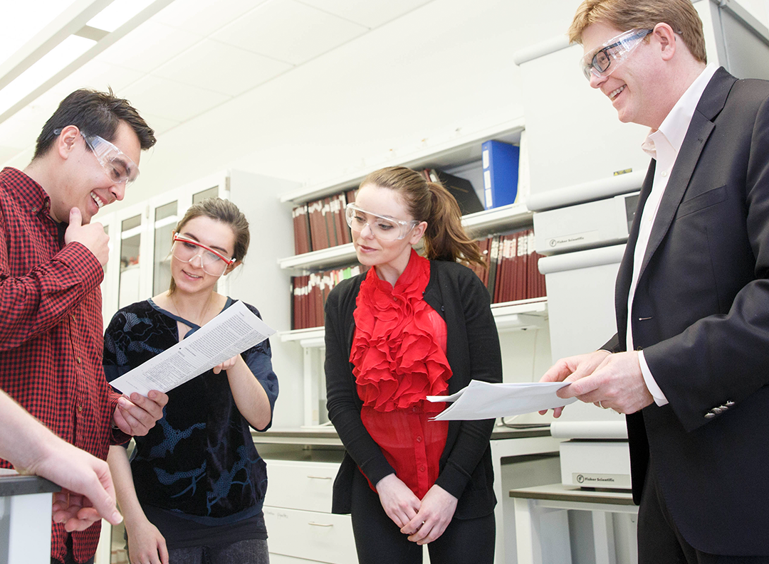a group of four people look at papers in a lab