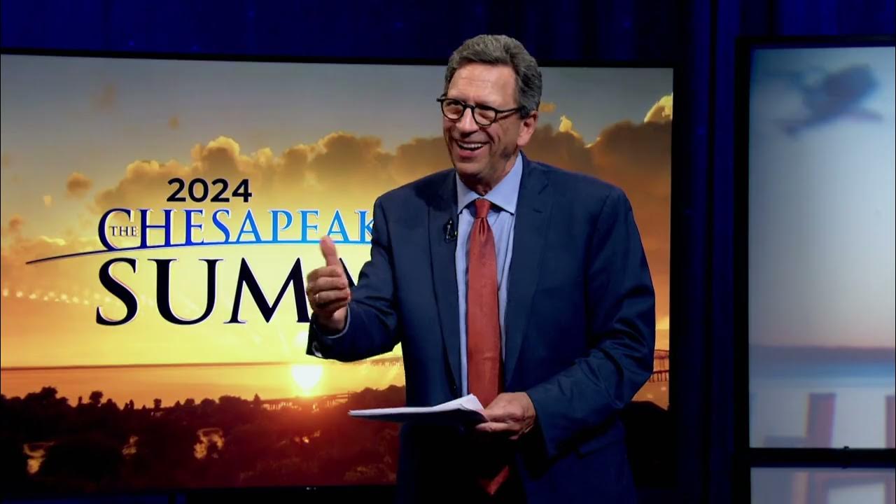 a man in a blue suit and red tie in front of a screen with a sunset. with text that reads: "2024 Chesapeake Bay Summit"