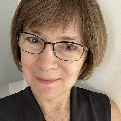 a woman with short light brown hair and glasses in a black tank top