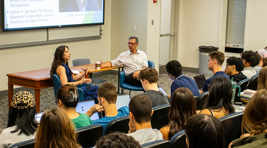Signature Courses a woman with brown hair and a man in white shirt speak in front of a full classroom