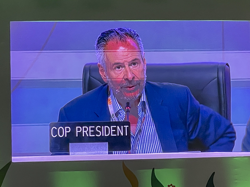 A man in a blue suit on a TV screen that reads COP President