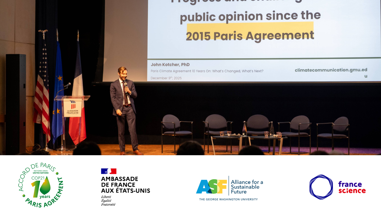 a man in a dark suit on stage in front of a screen
