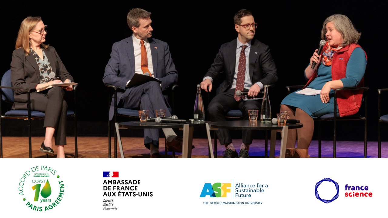 four people on stage on on the right in a red vest holds a microphone