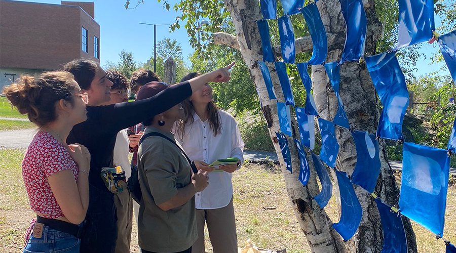 people outside pointing at blue fabric on a tree
