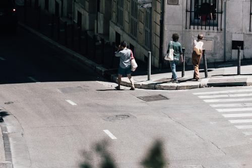 Pedestrians walking on a sidewalk on a shaded street