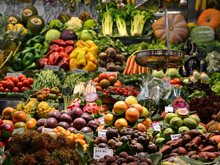 A colorful picture of various fruits and vegetables in a stall at Mercado de la Boqueria in Barcelona.