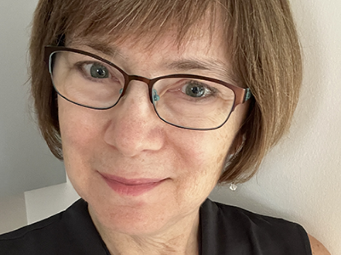 a woman with short light brown hair and glasses in a black tank top