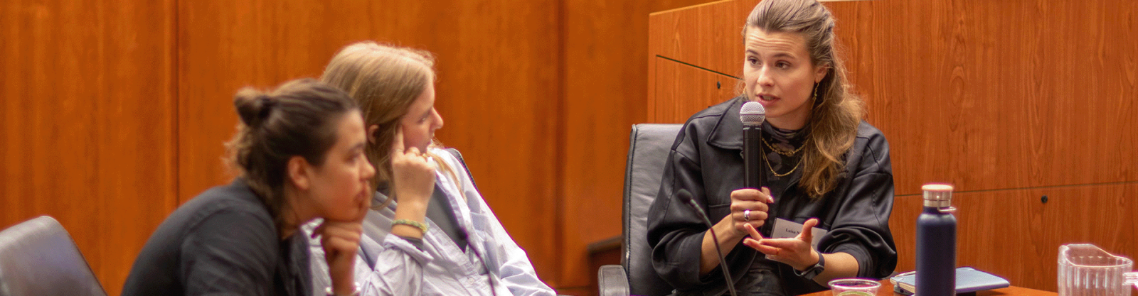 A student debates with a microphone and two peers nearby