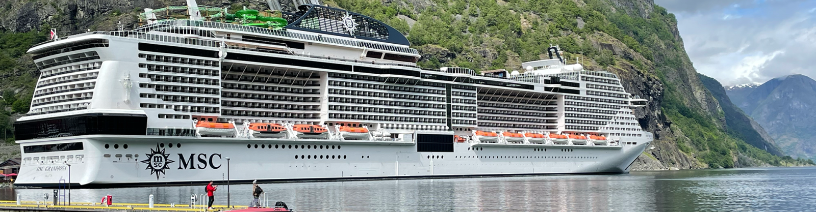 a large cruise ship in the water surrounded by mountains 