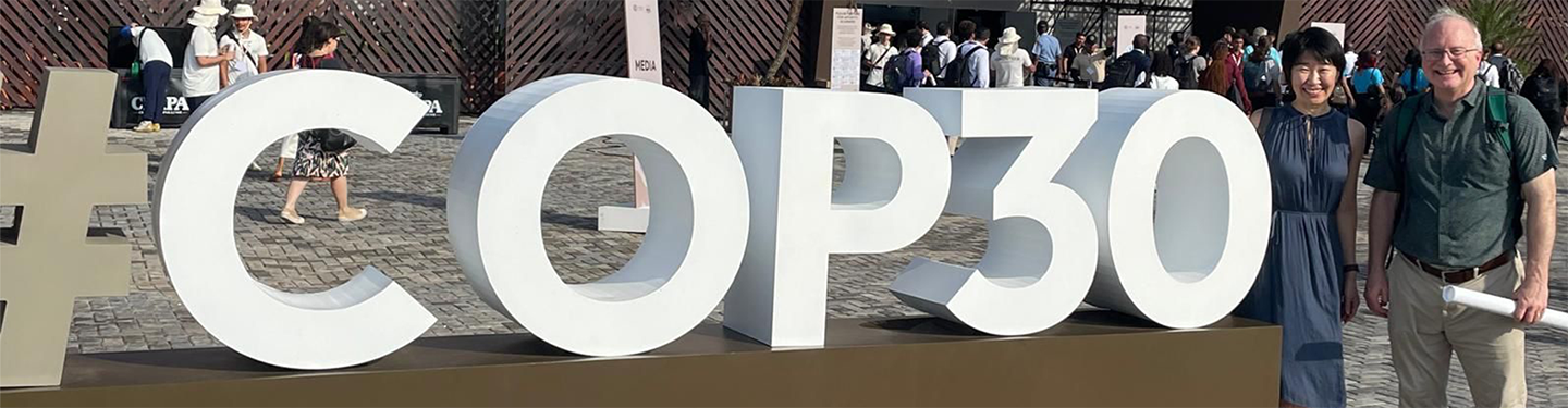 a big white sign that reads COP30 and two people standing to the right