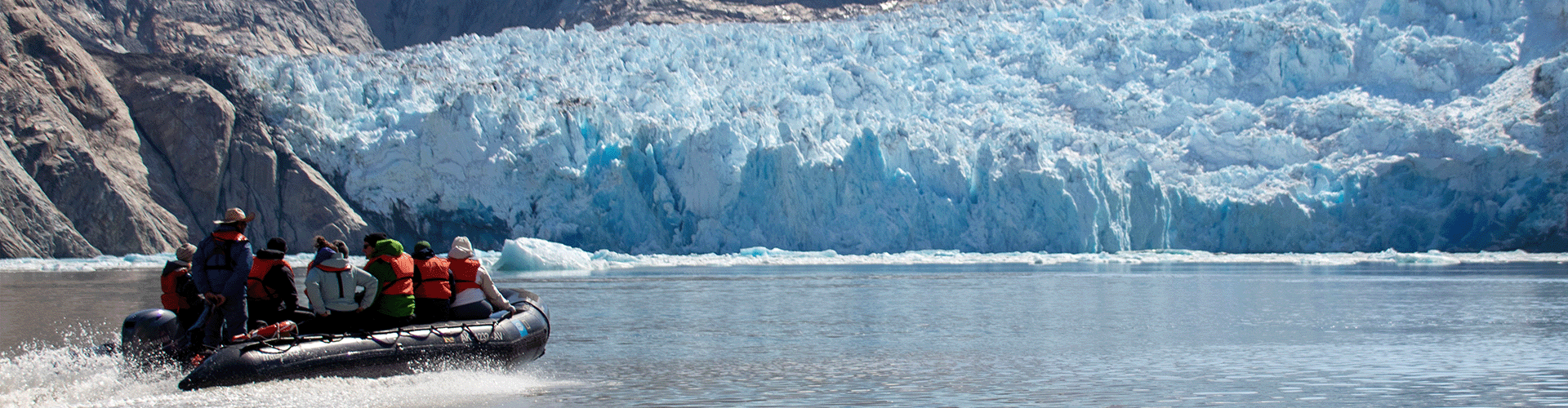 a motorized raft heads towards a glacier in the antartic 